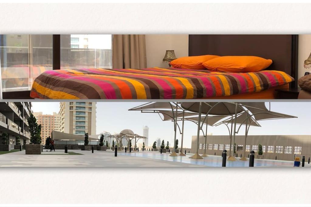 a bed with orange pillows and an umbrella at Sweet studio in Dubai Sports City in Dubai