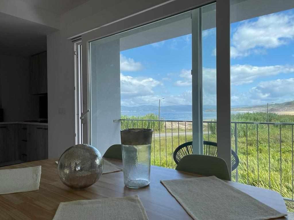 a dining room table with a view of a balcony at Mar de Queiruga: 01 As Seiras in Porto do Son