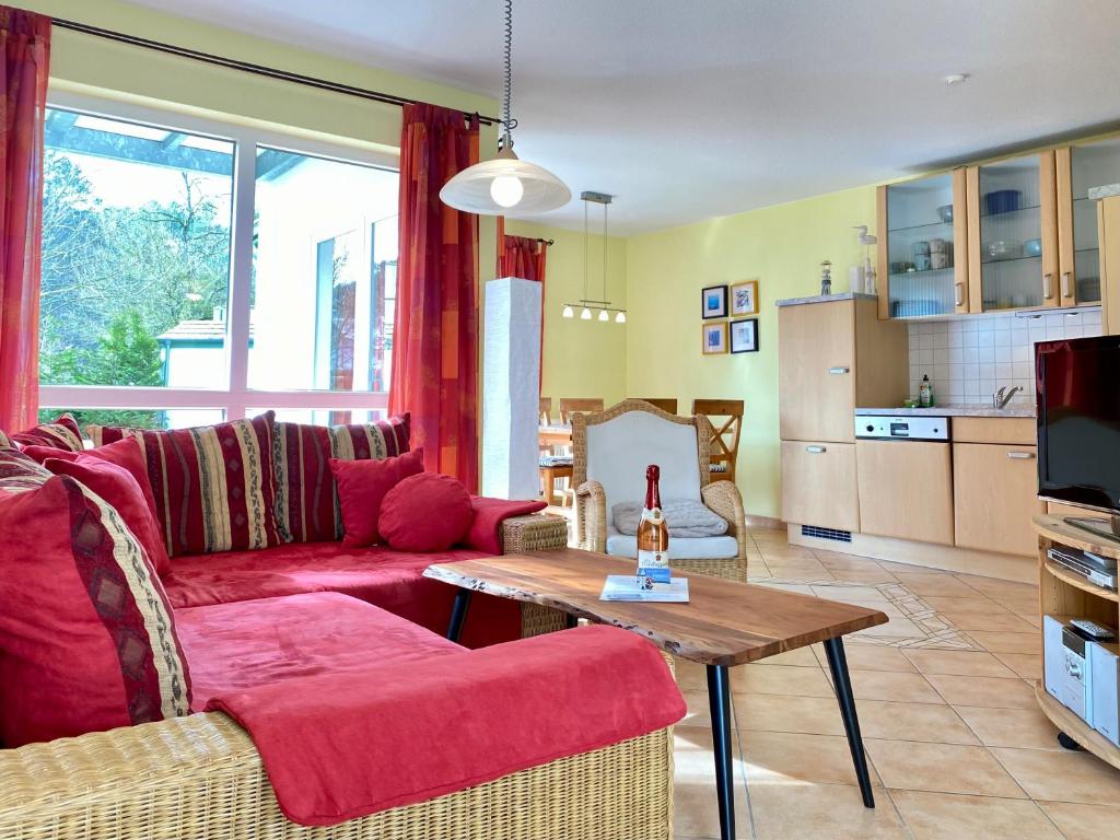 a living room with a red couch and a table at Dünenresidenz Karlshagen - Ferienwohnung am Gingsterweg in Karlshagen