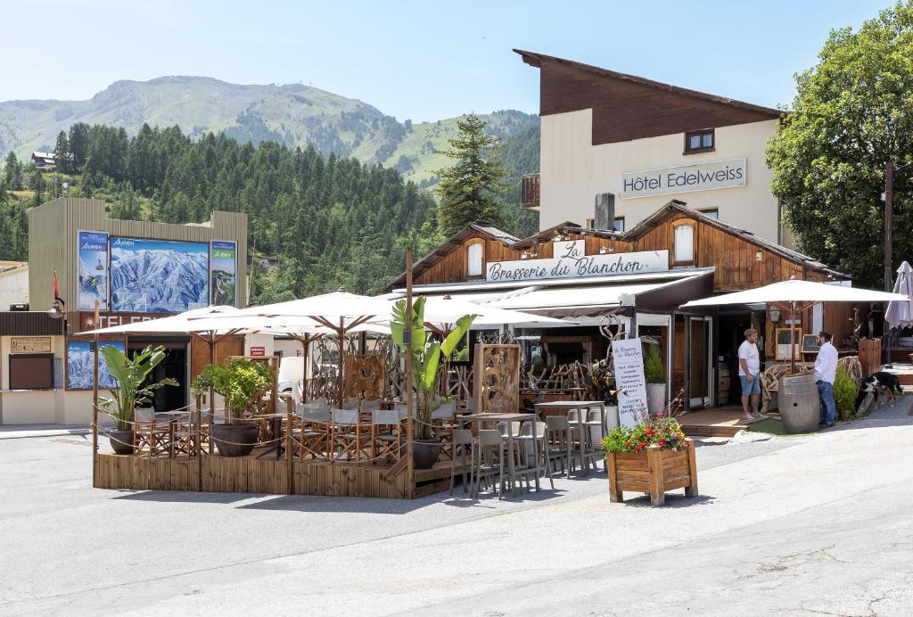 einen Markt mit Stühlen und Sonnenschirmen vor einem Gebäude in der Unterkunft Hotel Edelweiss in Auron