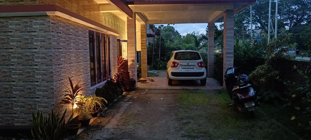 a white car parked in a garage next to a house at Mulberry Guesthouse in Guwahati