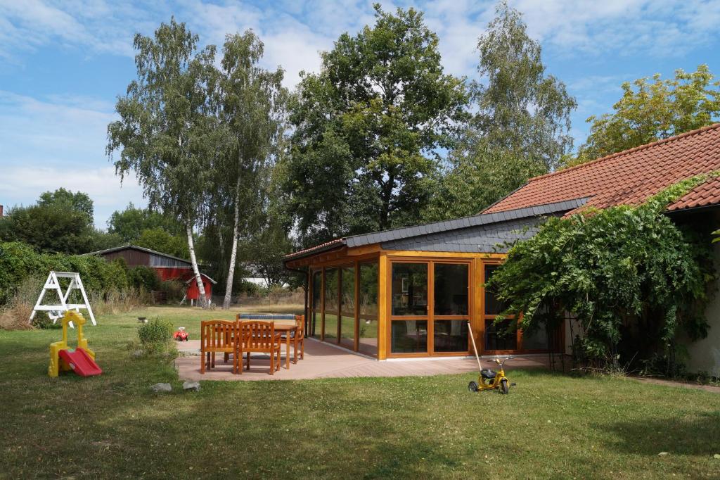 ein Haus mit Glastüren und einer Terrasse mit Spielplatz in der Unterkunft Das kleine Haus in Hornburg