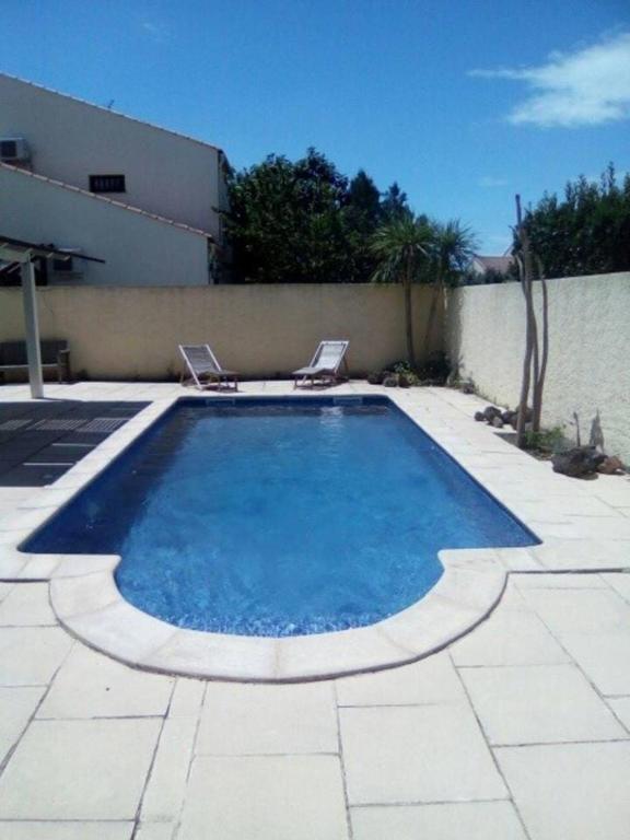 - une piscine avec 2 chaises assises à côté d'un bâtiment dans l'établissement Villa Agda, à Agde