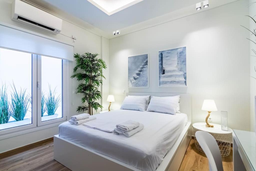 ein weißes Schlafzimmer mit einem Bett und einem Fenster in der Unterkunft Greek Island in Athen