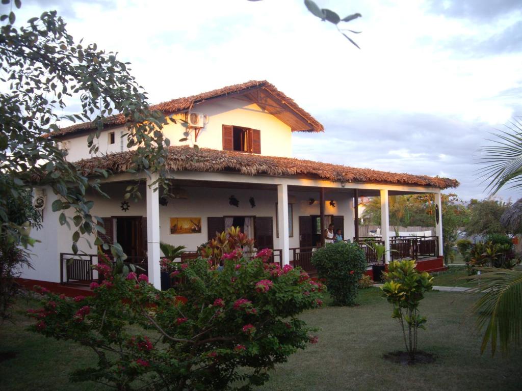 Villa ZAKIA في Madirokely: بيت ابيض مع شرفه وبعض الزهور
