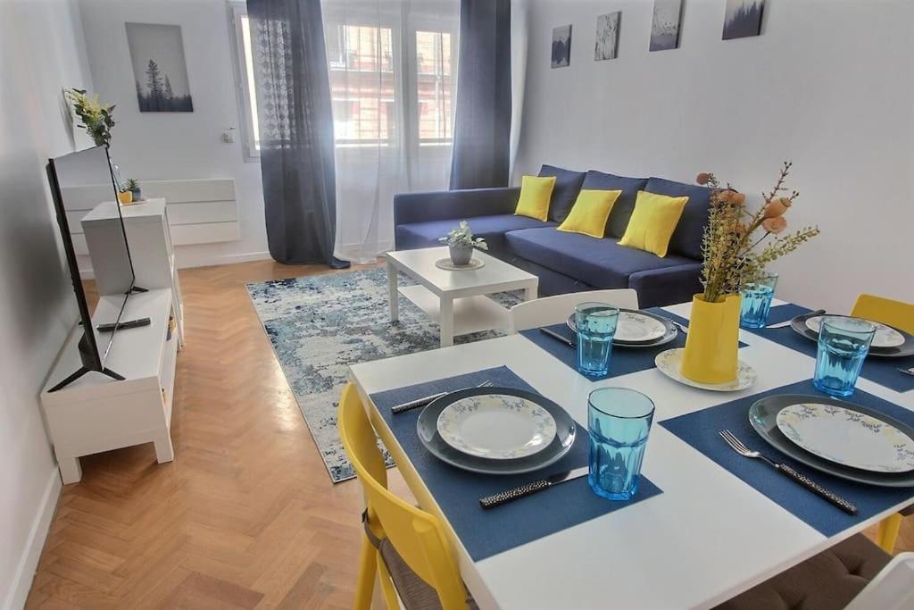 a living room with a table and a blue couch at Blue and Yellow House in Suresnes