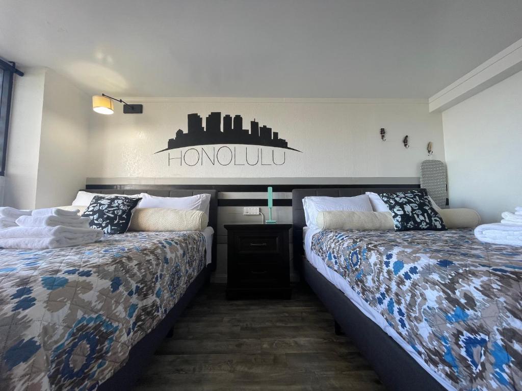 ein Schlafzimmer mit 2 Betten und ein Schild an der Wand in der Unterkunft *RareLayout*2Qn Beds*Great for Groups,Friends,Wakiki in Honolulu