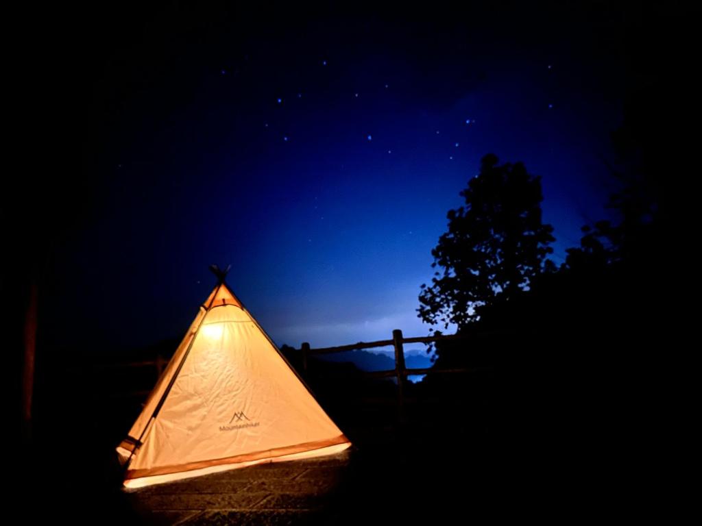 張家界市にあるZhangjiajie National Forest Park Campingの暗闇の中に座るライトアップテント