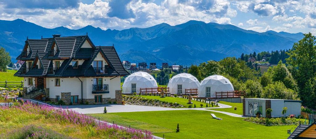 una casa en un campo con montañas en el fondo en Willa Pasieka Apartamenty Domki, en Bukowina Tatrzańska