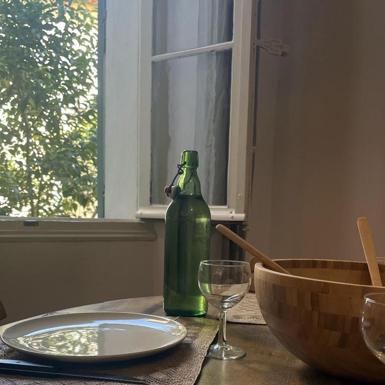 una mesa con una botella verde, un plato y un vaso en La Demeure du Pont Vieux, en Collobrières