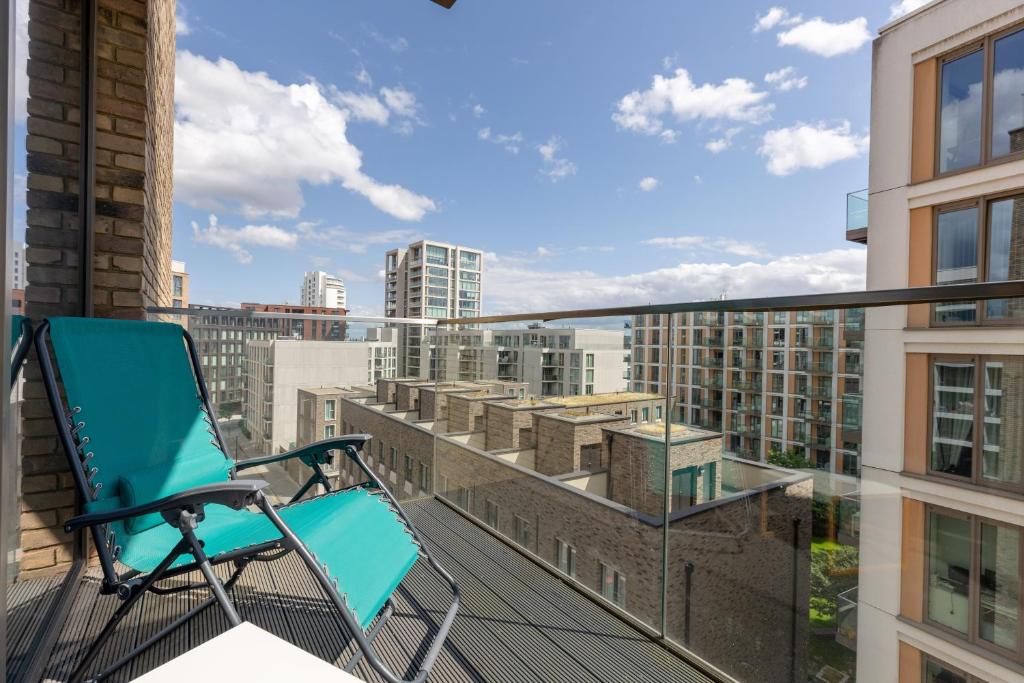 a blue chair sitting on the balcony of a building at Dockside Apartment With Scenic Views in London