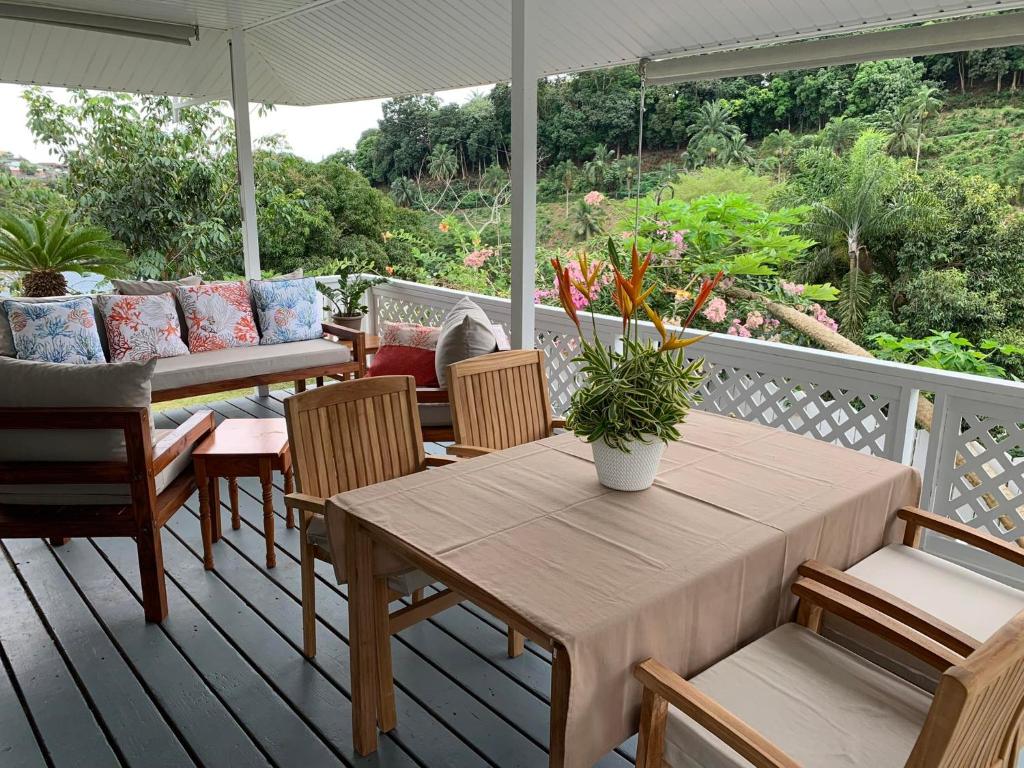 um alpendre com uma mesa, cadeiras e um guarda-sol em Fare Manatea 19 em Papeete