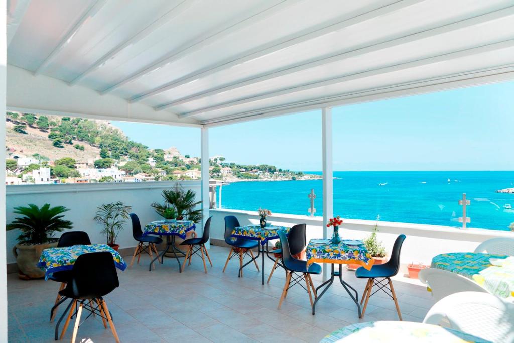 un patio con mesas y sillas y vistas al océano en B&B Una Terrazza sul Golfo di Sferracavallo, en Sferracavallo