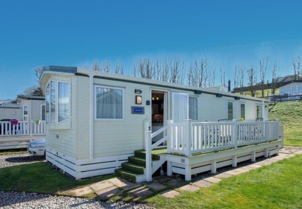 a white mobile home with a porch and stairs at Hillside Caravan in Dawlish
