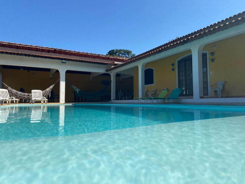 a swimming pool with chairs and a house at Pousada chácara amarela - Analandia SP in Analândia