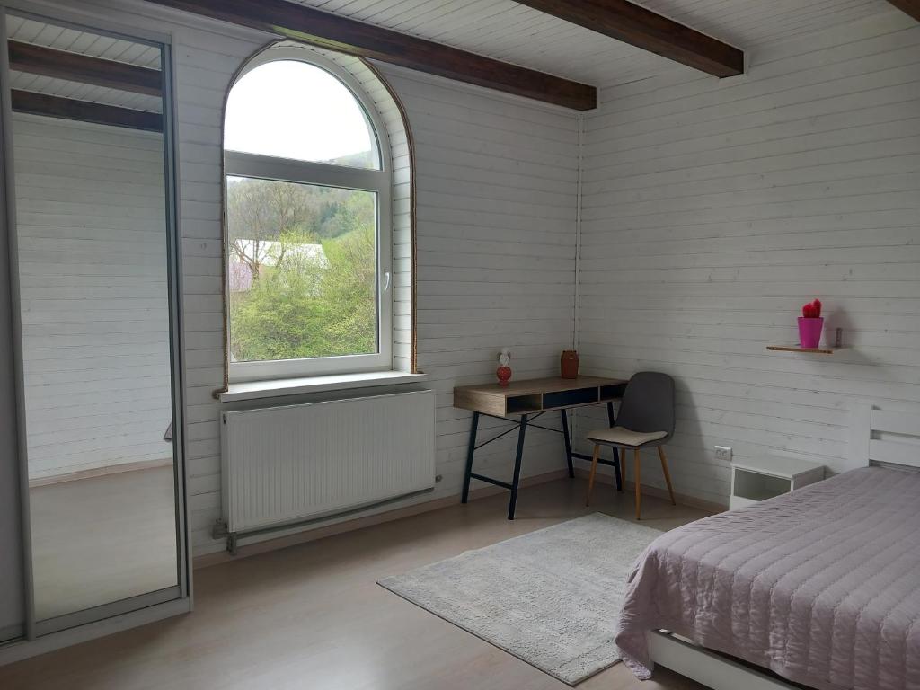 1 dormitorio con cama, escritorio y ventana en Садиба "Віталія", en Volovets