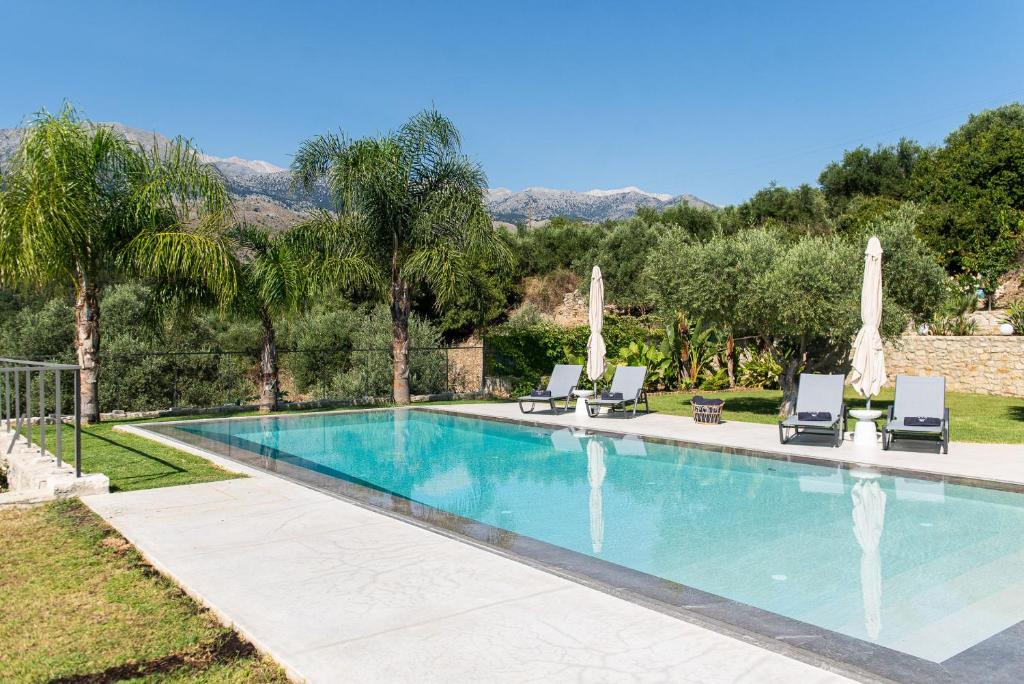 une piscine avec deux chaises longues et une villa dans l'établissement Villa Inati, à Nípos