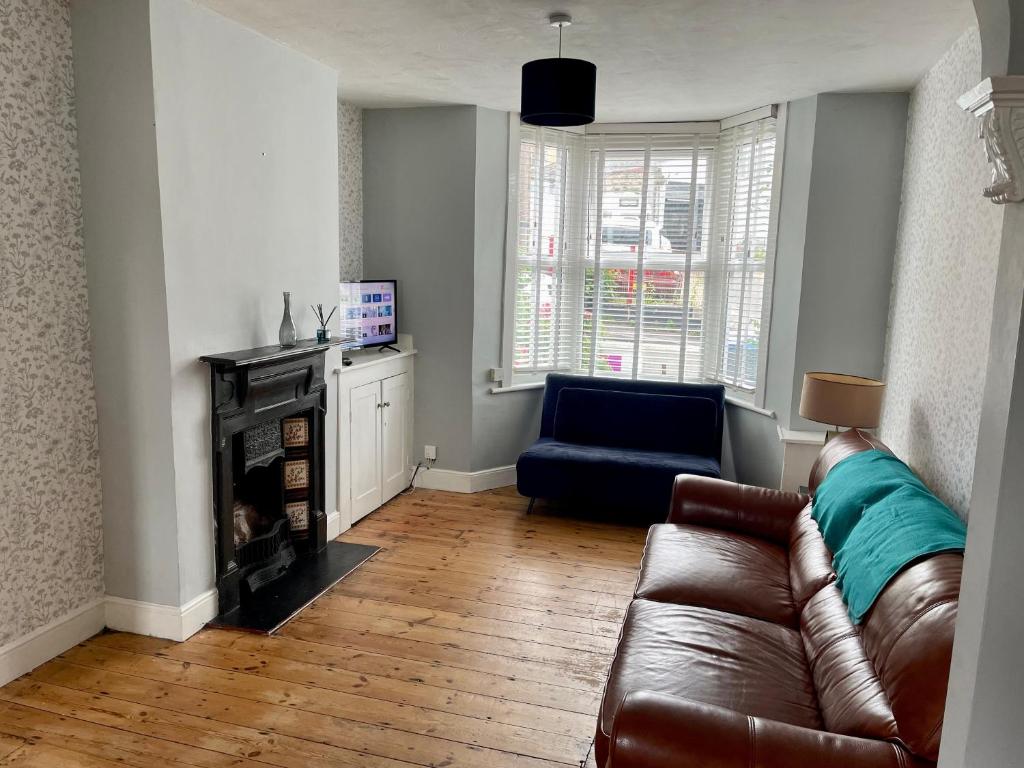 a living room with a leather couch and a chair at 2BD Victorian Terrace House Ramsgate in Ramsgate