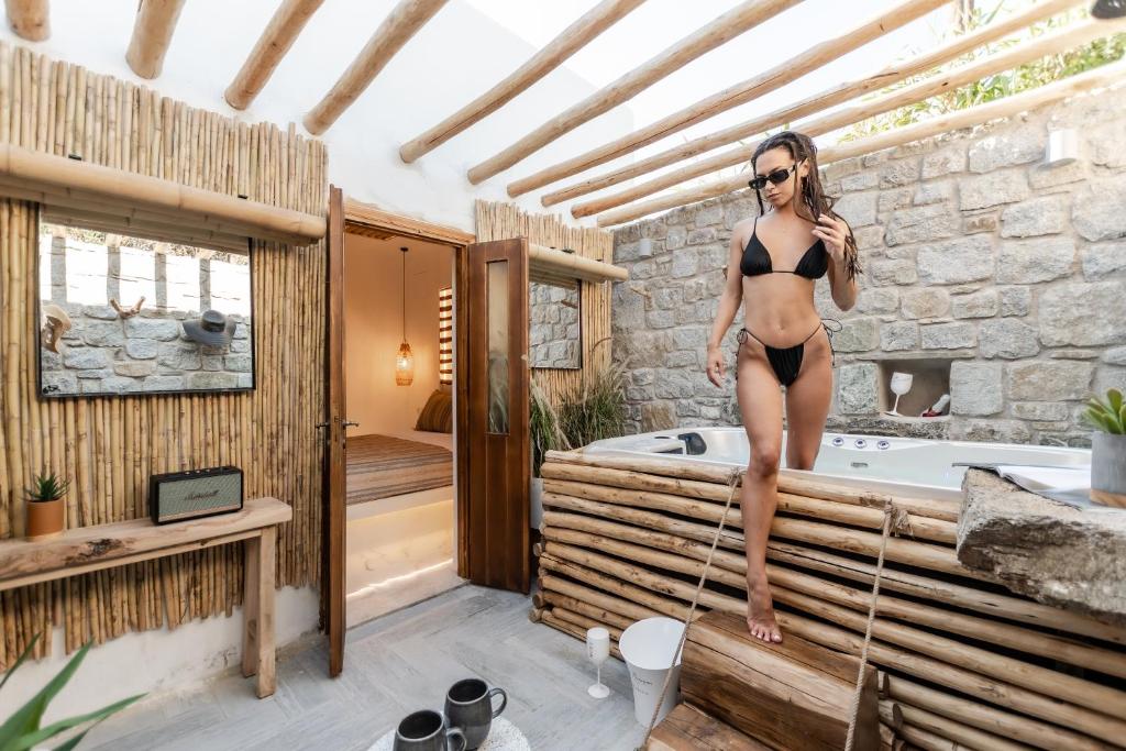 a woman in a bikini standing on the edge of a bath tub at Naxian Serenity Suites in Agia Anna Naxos