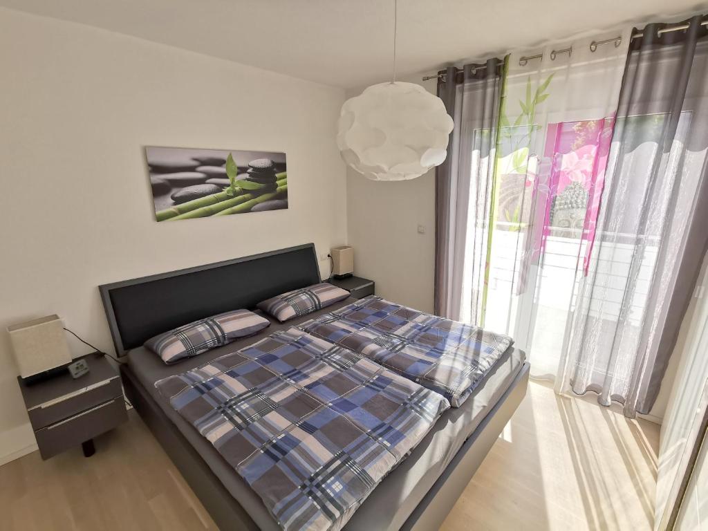 um quarto com uma cama e uma grande janela em Ferienwohnung Pinovas em Friedrichshafen