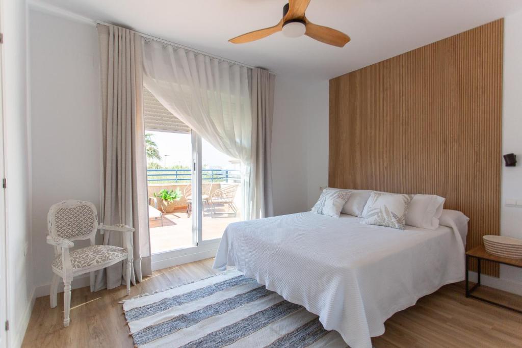 a white bedroom with a bed and a window at Aires de Doñana. Piscina y Playa. Parking gratis. in Sanlúcar de Barrameda