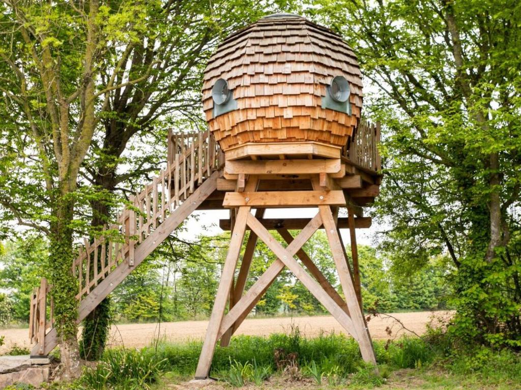 a wooden tree house sitting on top of a wooden stand at La Ville Es Renais - ferme et maison d'hôtes insolite in Erquy