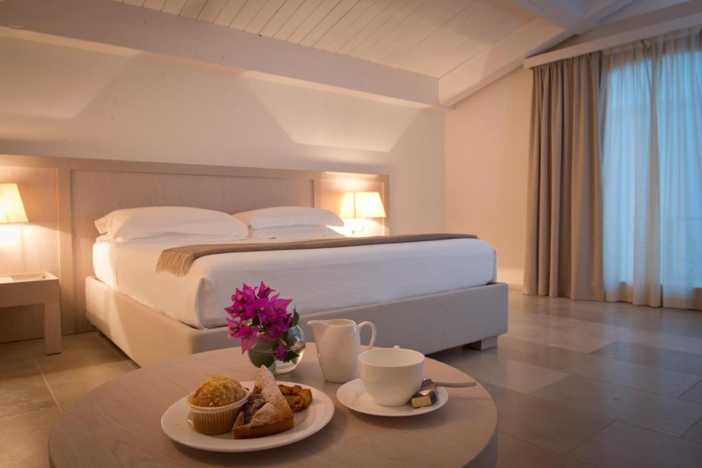 una camera d'albergo con letto e tavolo con cibo di Histò San Pietro Sul Mar Piccolo a Taranto