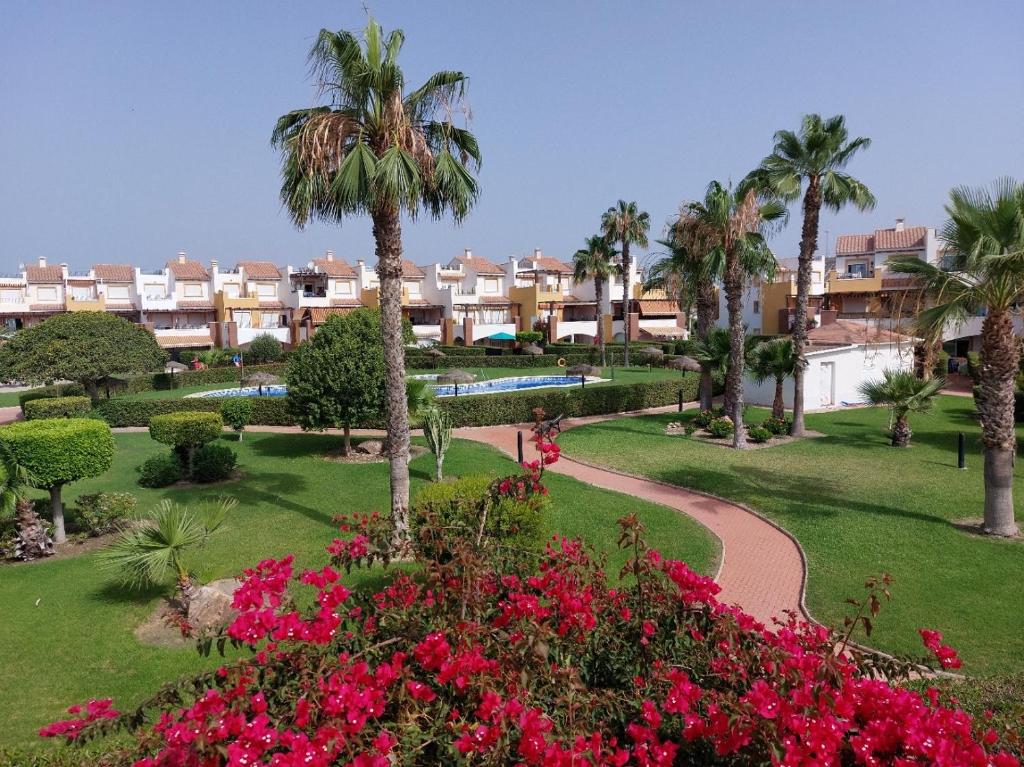 a park with flowers and palm trees and buildings at MojacarProperty, Apto Mirador Vera Playa in Vera