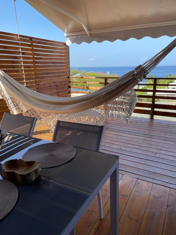 a hammock on a deck with a table and chairs at Bungalows Lanar'am Kaladja -1 in Bouillante