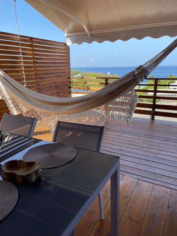 una hamaca en una terraza con mesa y sillas en Bungalows Lanar'am Kaladja -1, en Bouillante