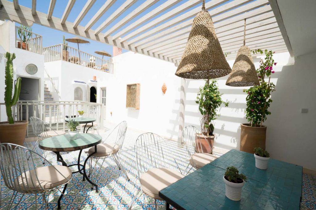 un patio avec des tables, des chaises et des plantes en pot dans l'établissement Riad l'Ayel d'Essaouira, à Essaouira