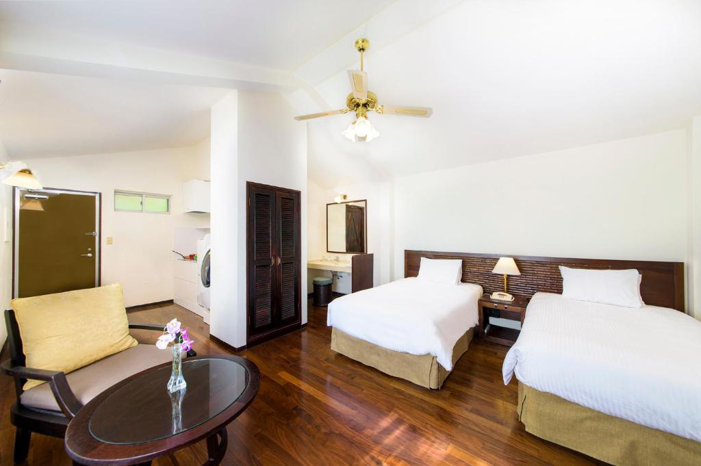 うるま市にあるココ ガーデンリゾート オキナワのベッド2台とテーブルが備わるホテルルームです。