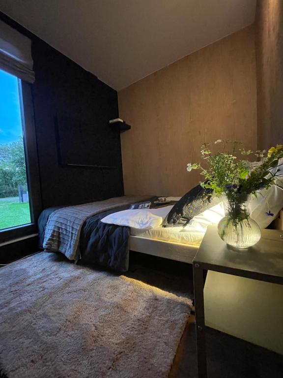 1 dormitorio con 1 cama y un jarrón de flores sobre una mesa en kontener nad rzeką 