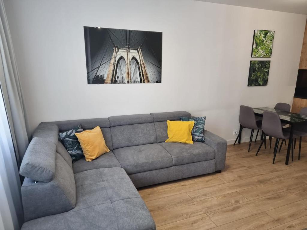 a living room with a gray couch with yellow pillows at Apartament Near Sky Tower Free Parking for 2 cars in Wrocław
