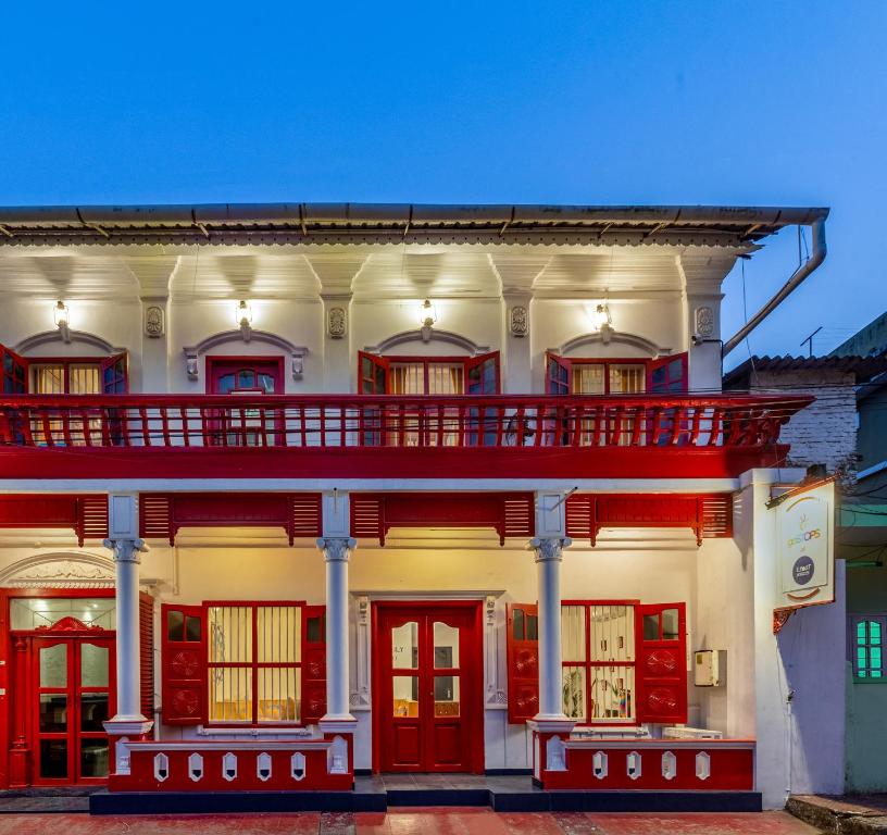 Edificio blanco con puertas rojas y balcón en goSTOPS Kochi, en Kochi