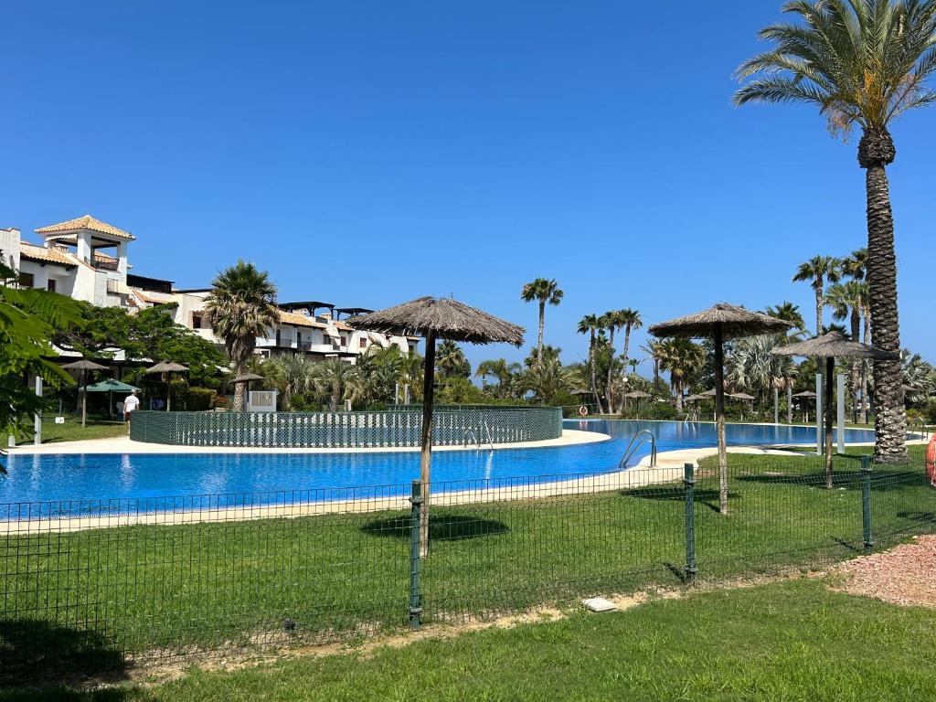einen Pool mit Sonnenschirmen vor einem Resort in der Unterkunft Ático junto al Mar,Acceso directo a la playa,Jardines de Nuevo Vera,WIFI in Vera