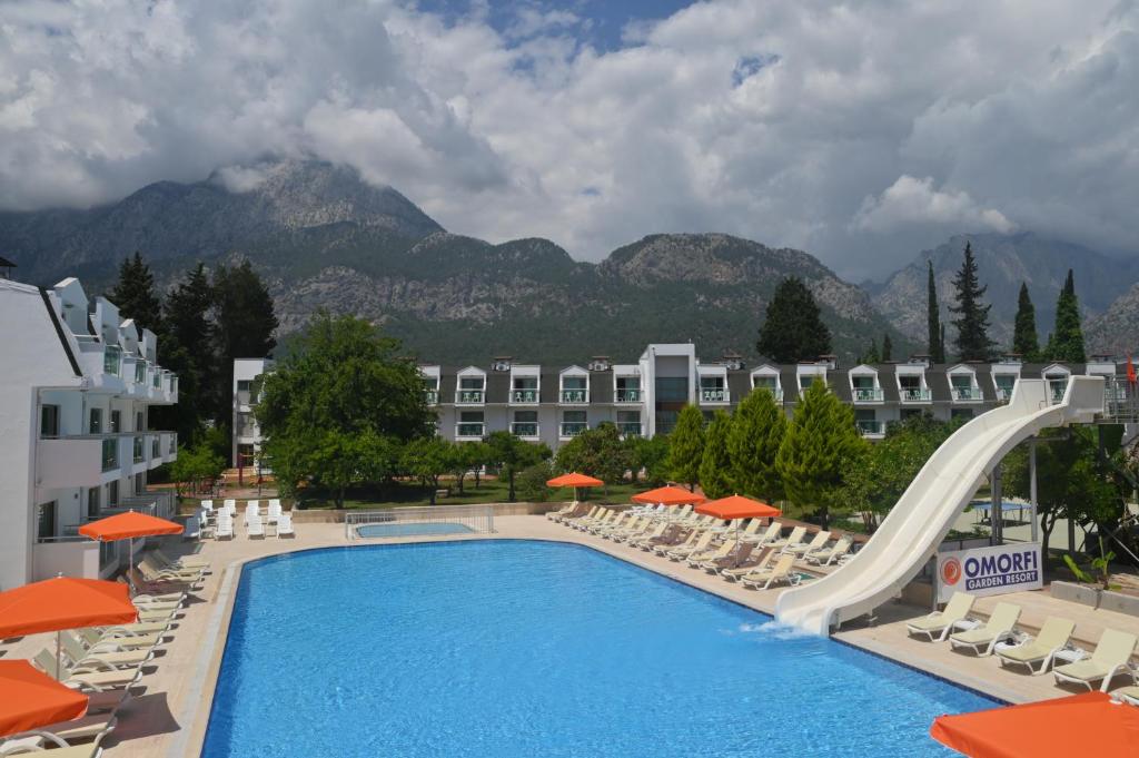 una piscina resort con sillas y un tobogán en OMORFİ GARDEN RESORT, en Dedeköy