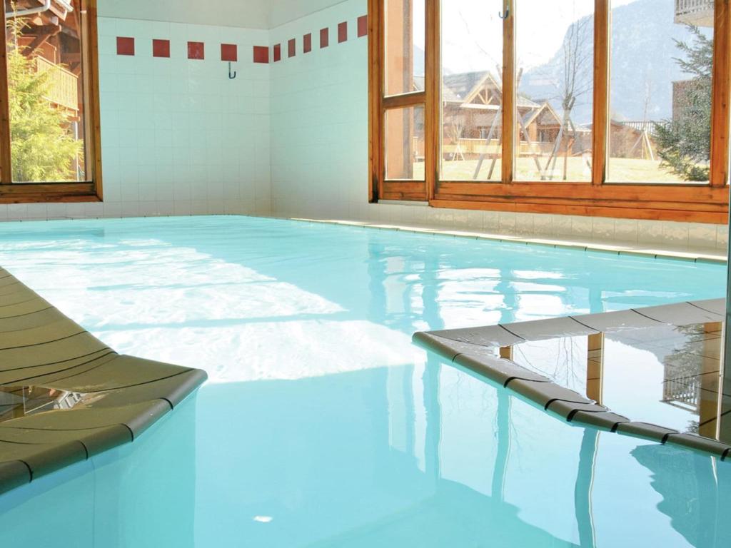 una piscina de agua azul en una habitación con ventanas en Attractive apartment with a balcony in Le Grand Massif, en Samoëns
