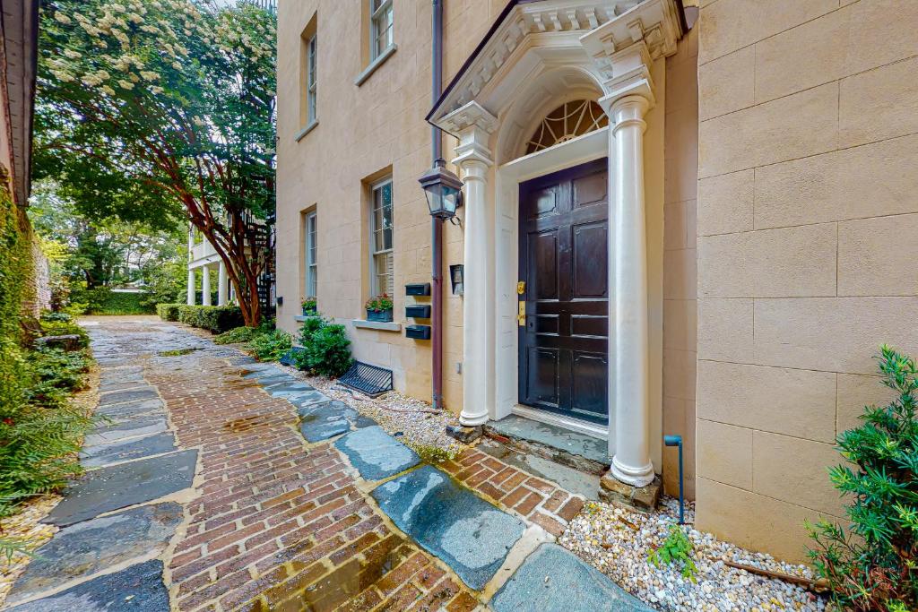 a building with a black door and a brick sidewalk at Rainbow Row Pied-A-Terre in Charleston