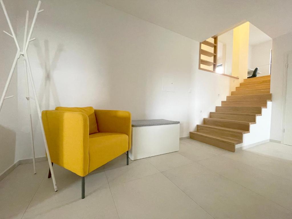 a living room with a yellow chair and stairs at Garden Villa in Štanjel