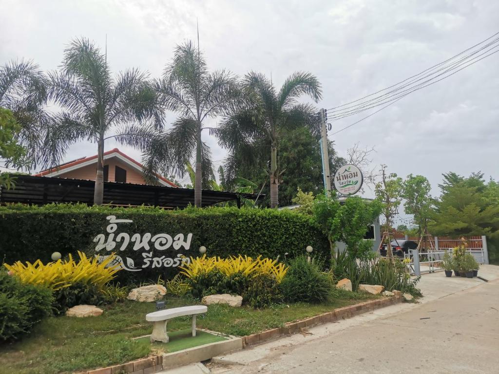a bench in a park with palm trees and a building at Numhom Resort in Ban Nong Chum Saeng