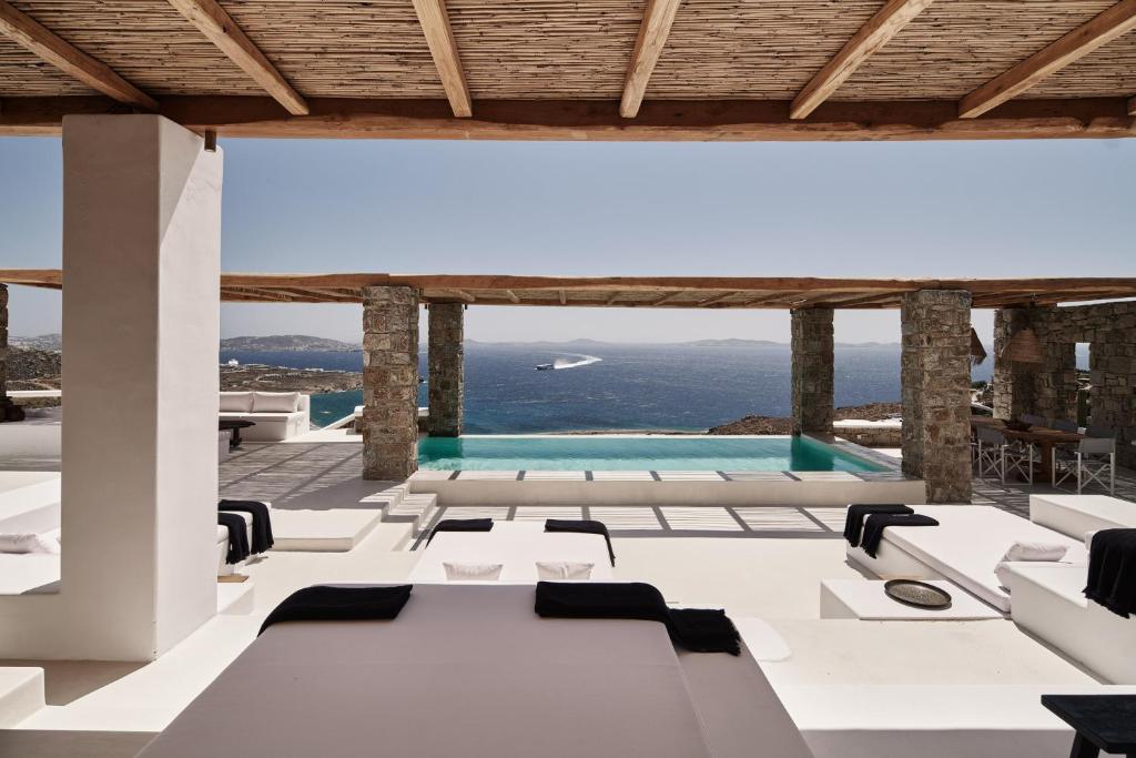 HoulakiaにあるVilla La Piscine Mykonosの白いテーブルと椅子、スイミングプールが備わる客室です。