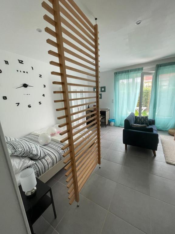 1 dormitorio con 1 cama y reloj en la pared en Studio meuble Kenaya 29m2. en Saint-Étienne-du-Rouvray