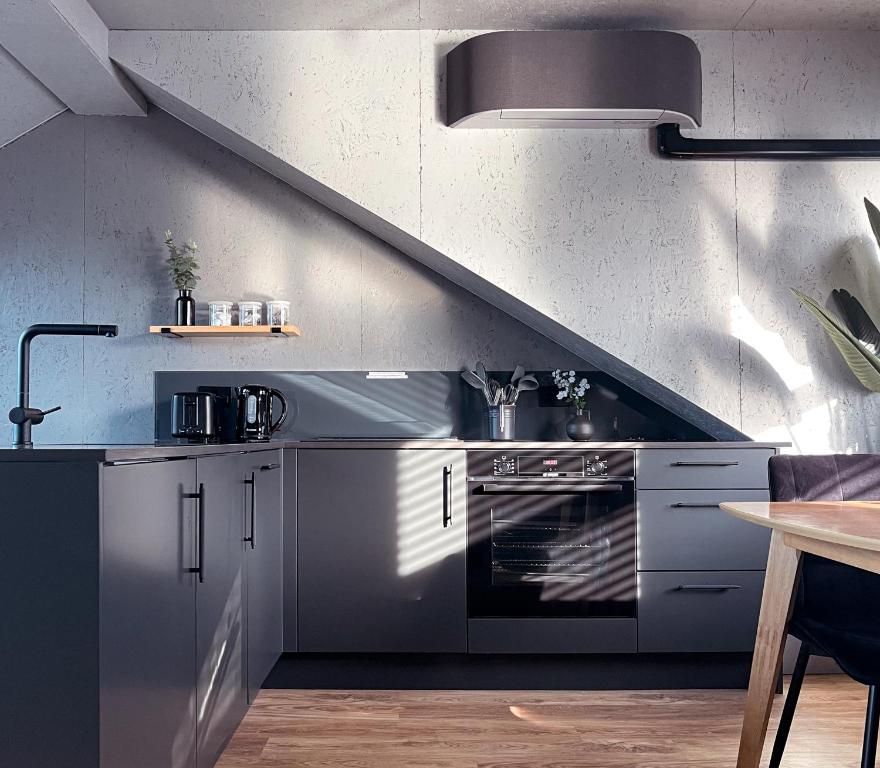 a kitchen with stainless steel appliances and a staircase at Stylish Urban Retreat In West London in Brentford