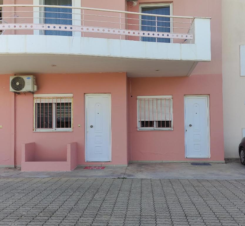 - un bâtiment rose avec deux portes et un balcon dans l'établissement Olga & Dimitris, à Kalamata