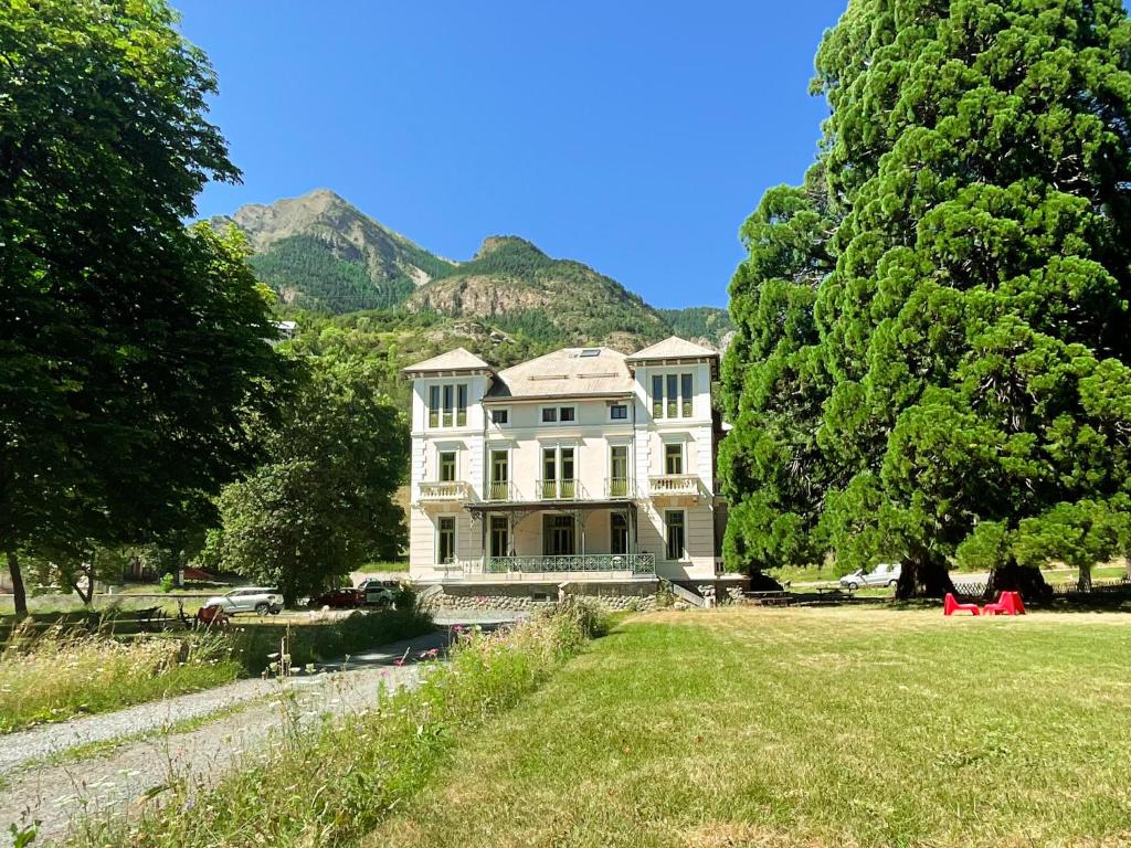 a large white house with mountains in the background at SUITE dans VILLA MEXICAINE in Jausiers