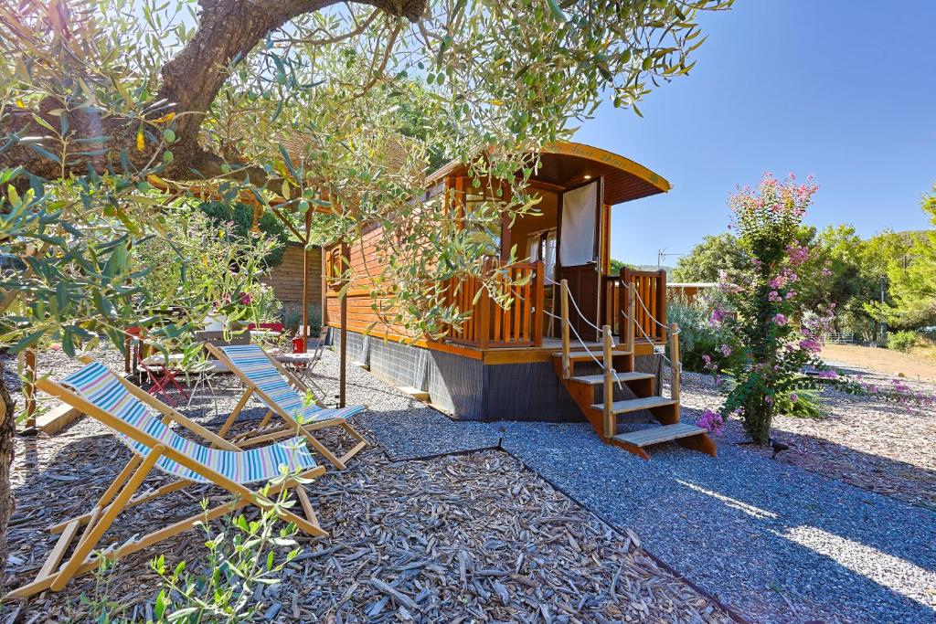 une petite cabane dans les arbres avec deux chaises et un escalier dans l'établissement Roulotte au cœur des vignes, Hyères, à Hyères