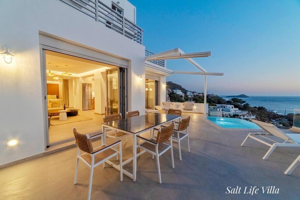 a dining room with a table and chairs and the ocean at Salt Life Villa in Kalymnos