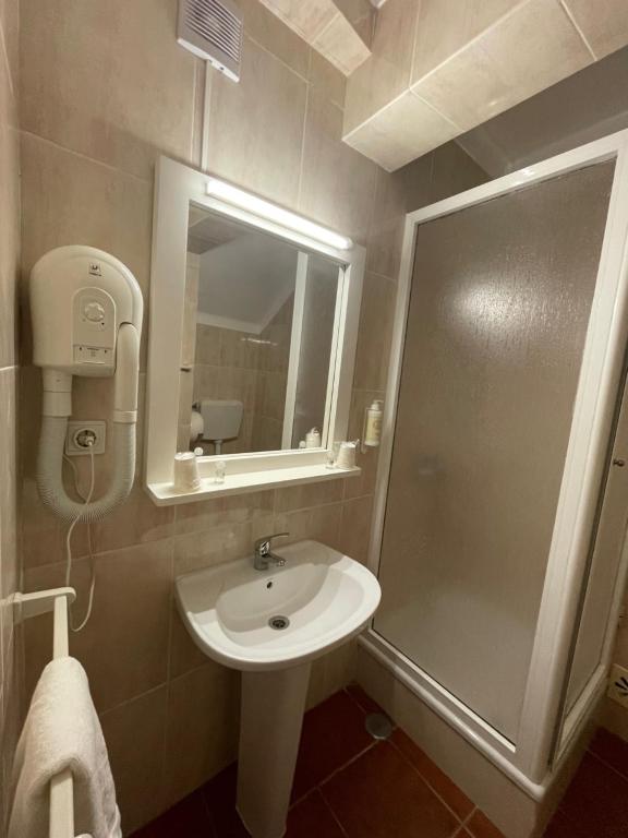 y baño con lavabo y ducha con espejo. en Alojamento S. João, en Peniche