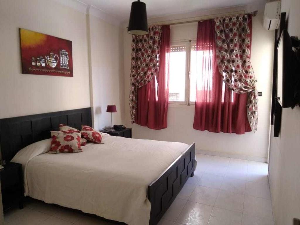 a bedroom with a large bed with red curtains at Bel appartement plein centre avec double terrasse in Oujda